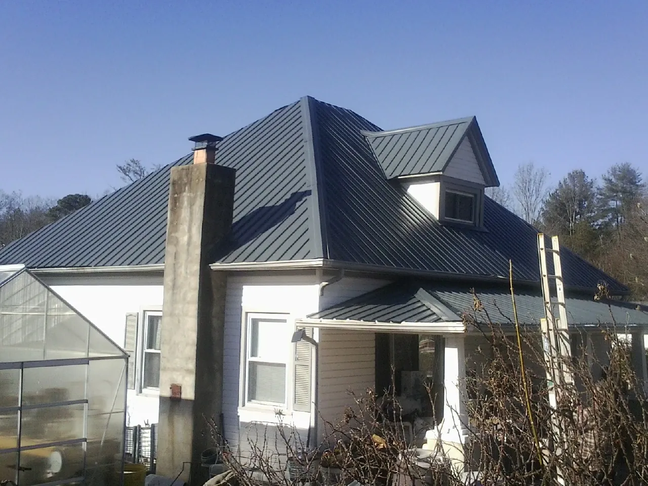 Dark blue standing seam metal roof on a white farmhouse with dormer — Slate & Tile Roof Repair by Roofing Brothers in Manzanita