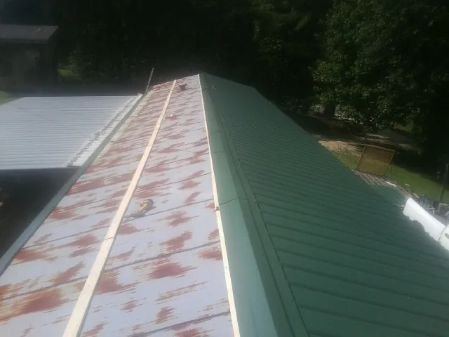 Old rusted panels beside newly installed green metal roofing — Wind Damage Roof Repair by Roofing Brothers in Manzanita
