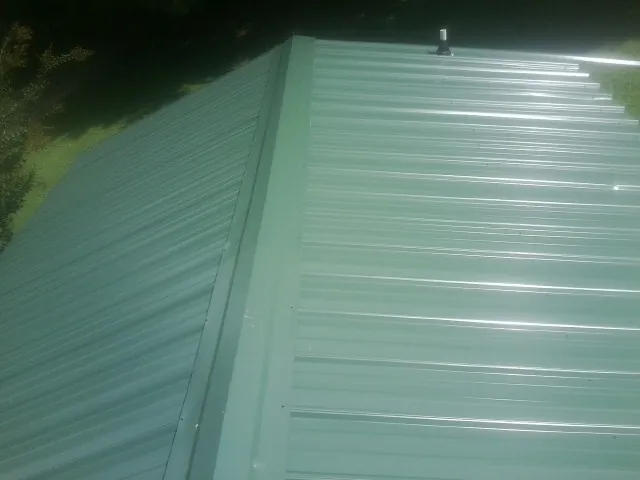 New green metal panels meeting at the ridge of a roof — Flat Roof Repair work by our crew in Manzanita