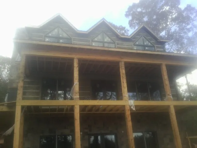 Dormers and porch framing on a large log home under construction — Roof Coating work by our crew in Manzanita