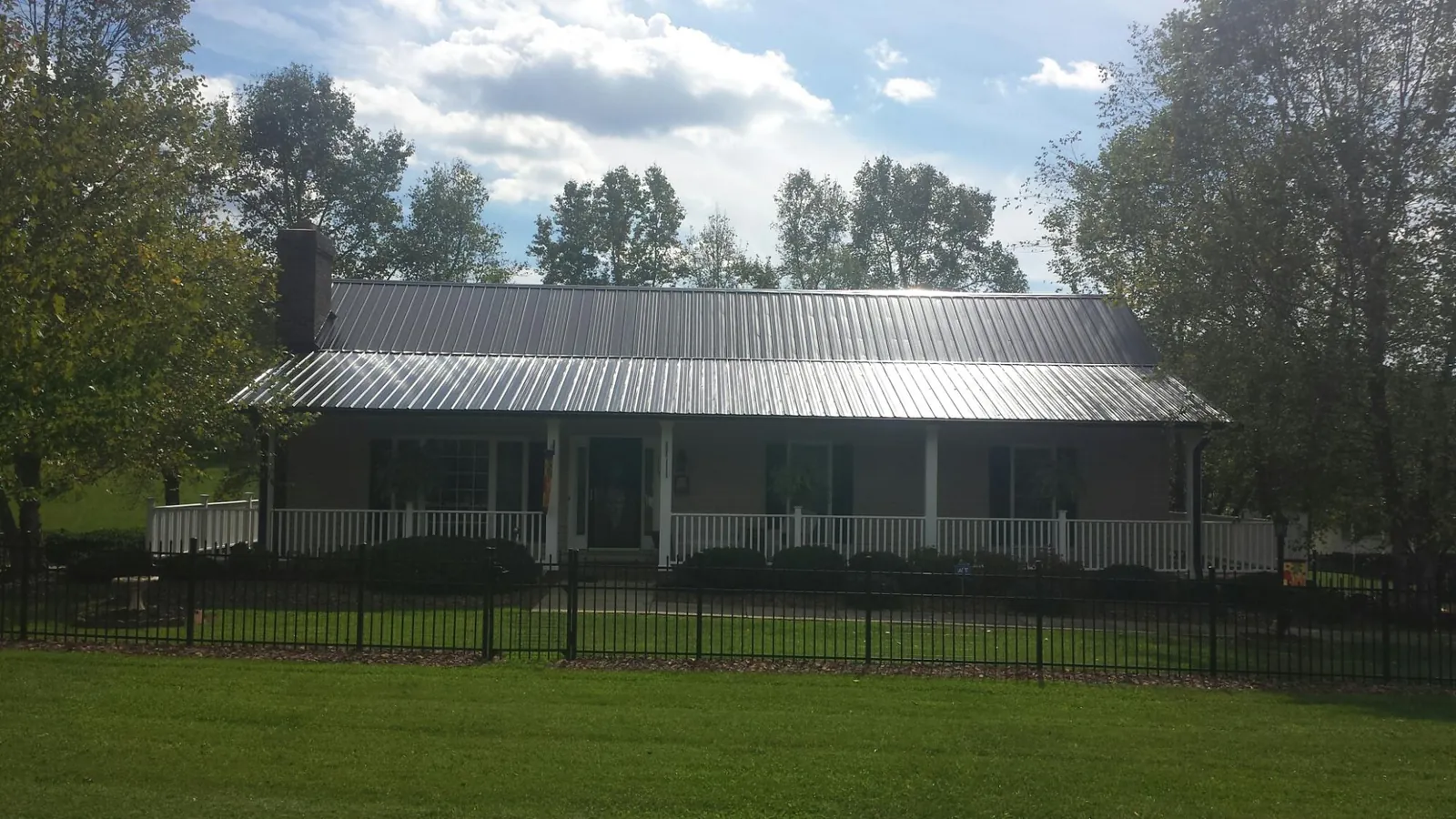 Gray metal roof on a brick ranch with a full width front porch — Gutter Guard Installation work by our crew in Manzanita
