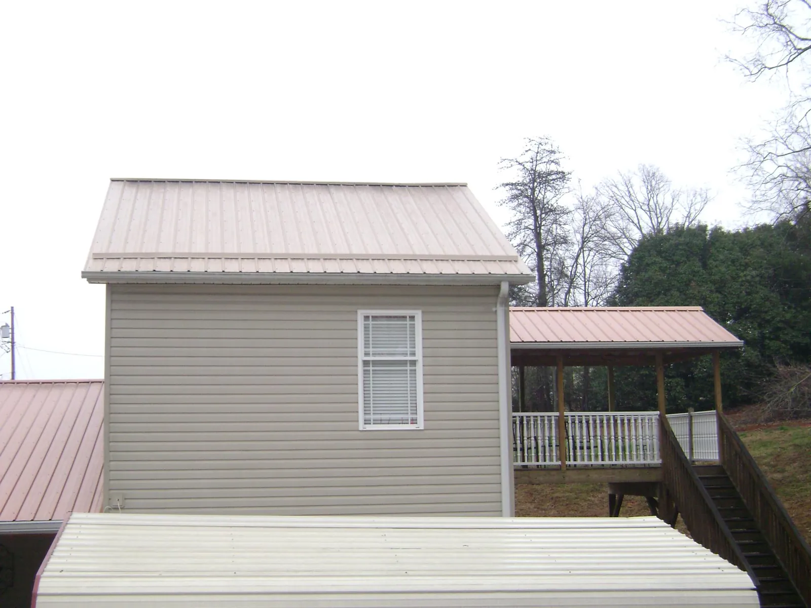 Tan metal roofs on a two story addition and attached porch, from a Roof Replacement job in Manzanita